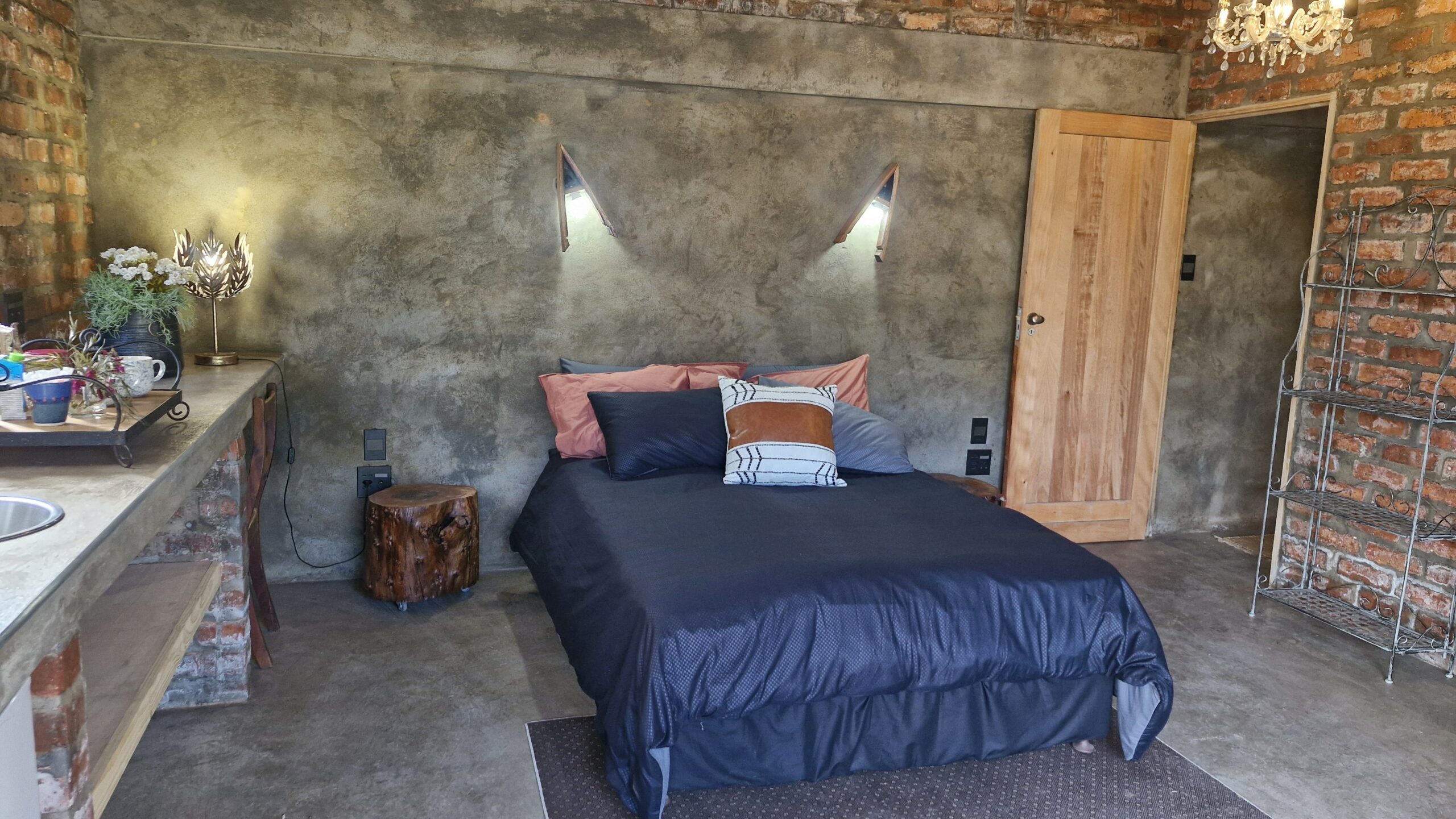 Group of people playing volleyball on a grassy area with a wooden bench labeled "DIE HOUTHUIS" in the foreground and dogs resting nearby.