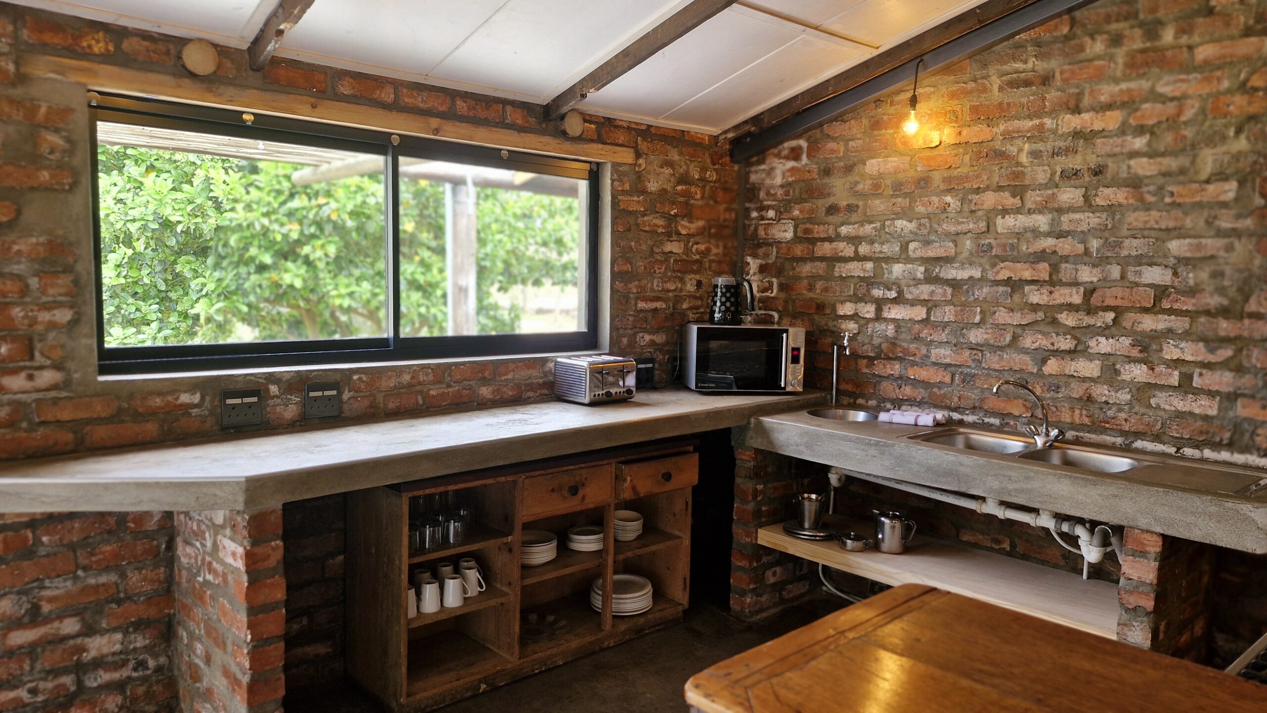 Group of people playing volleyball on a grassy area with a wooden bench labeled "DIE HOUTHUIS" in the foreground and dogs resting nearby.