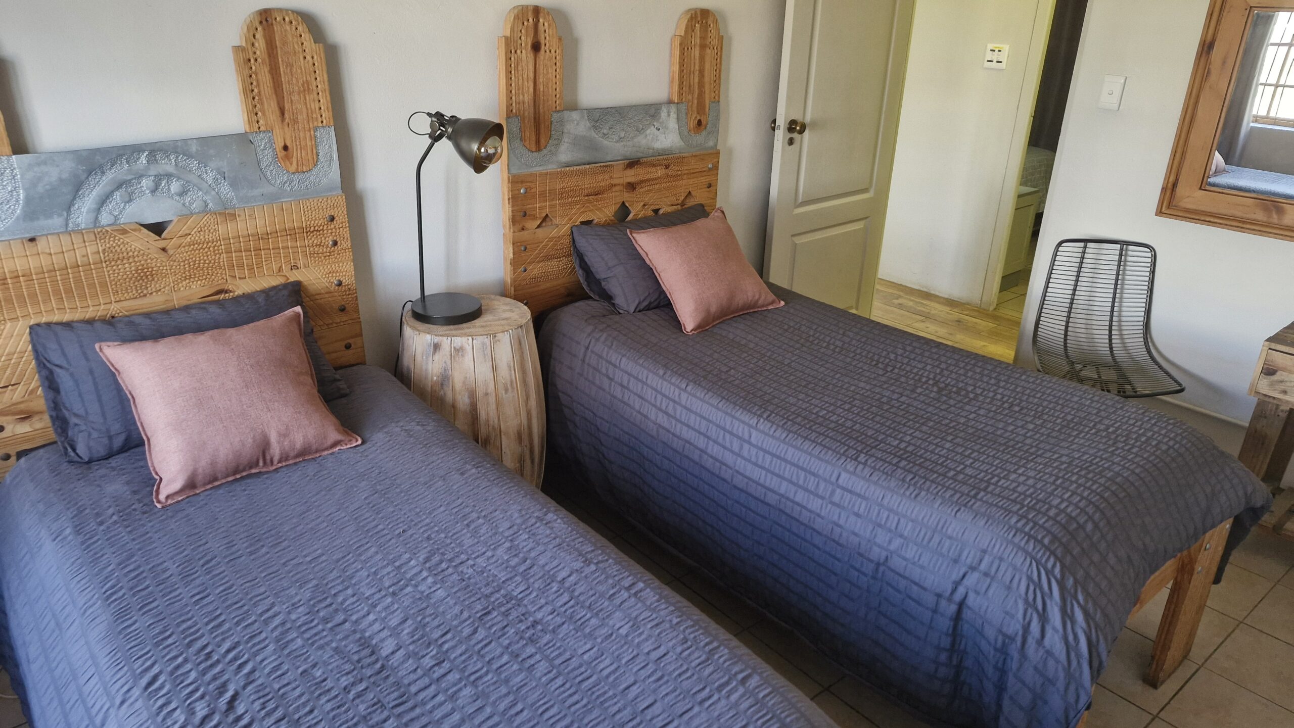 Group of people playing volleyball on a grassy area with a wooden bench labeled "DIE HOUTHUIS" in the foreground and dogs resting nearby.
