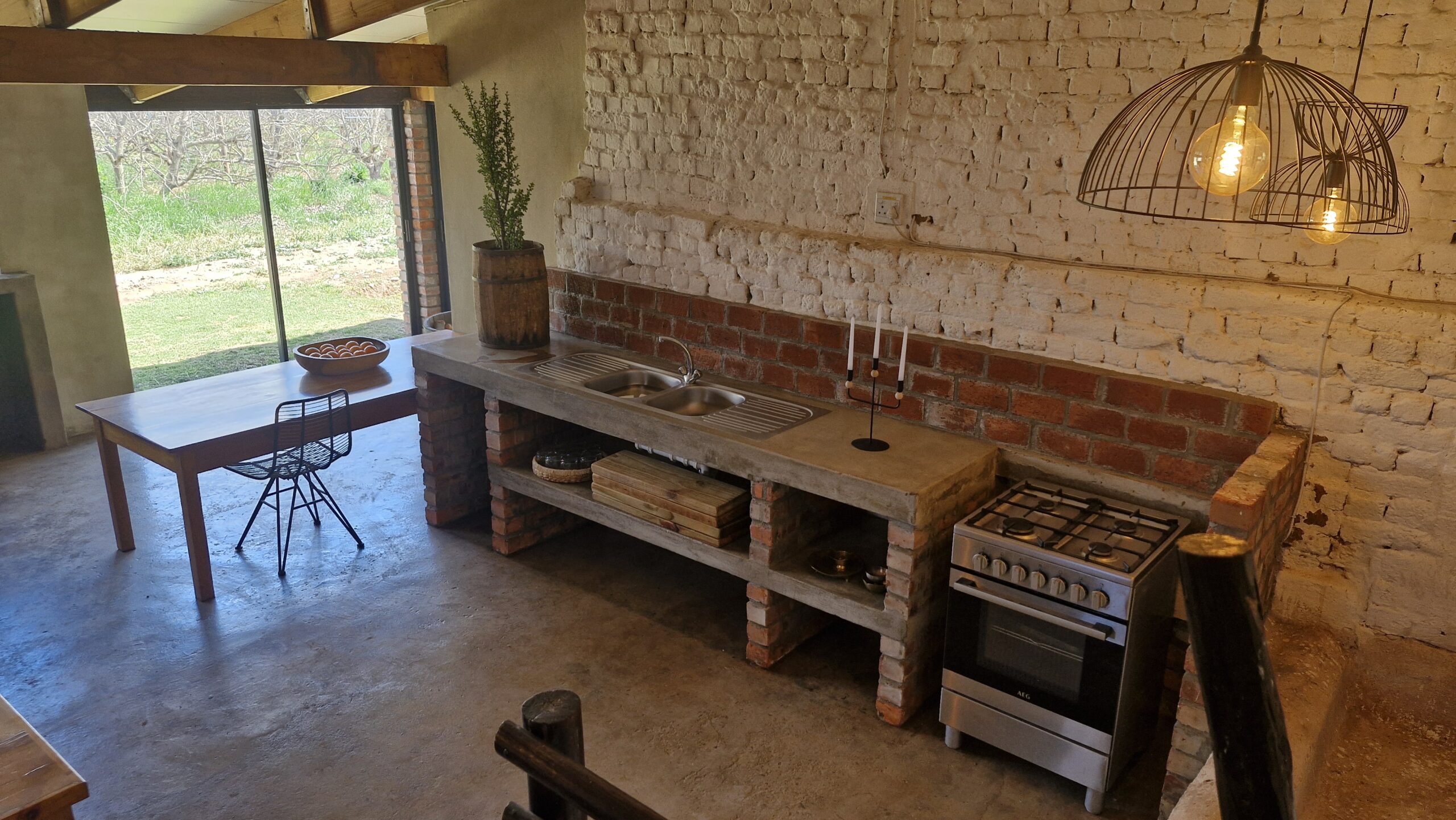 Group of people playing volleyball on a grassy area with a wooden bench labeled "DIE HOUTHUIS" in the foreground and dogs resting nearby.
